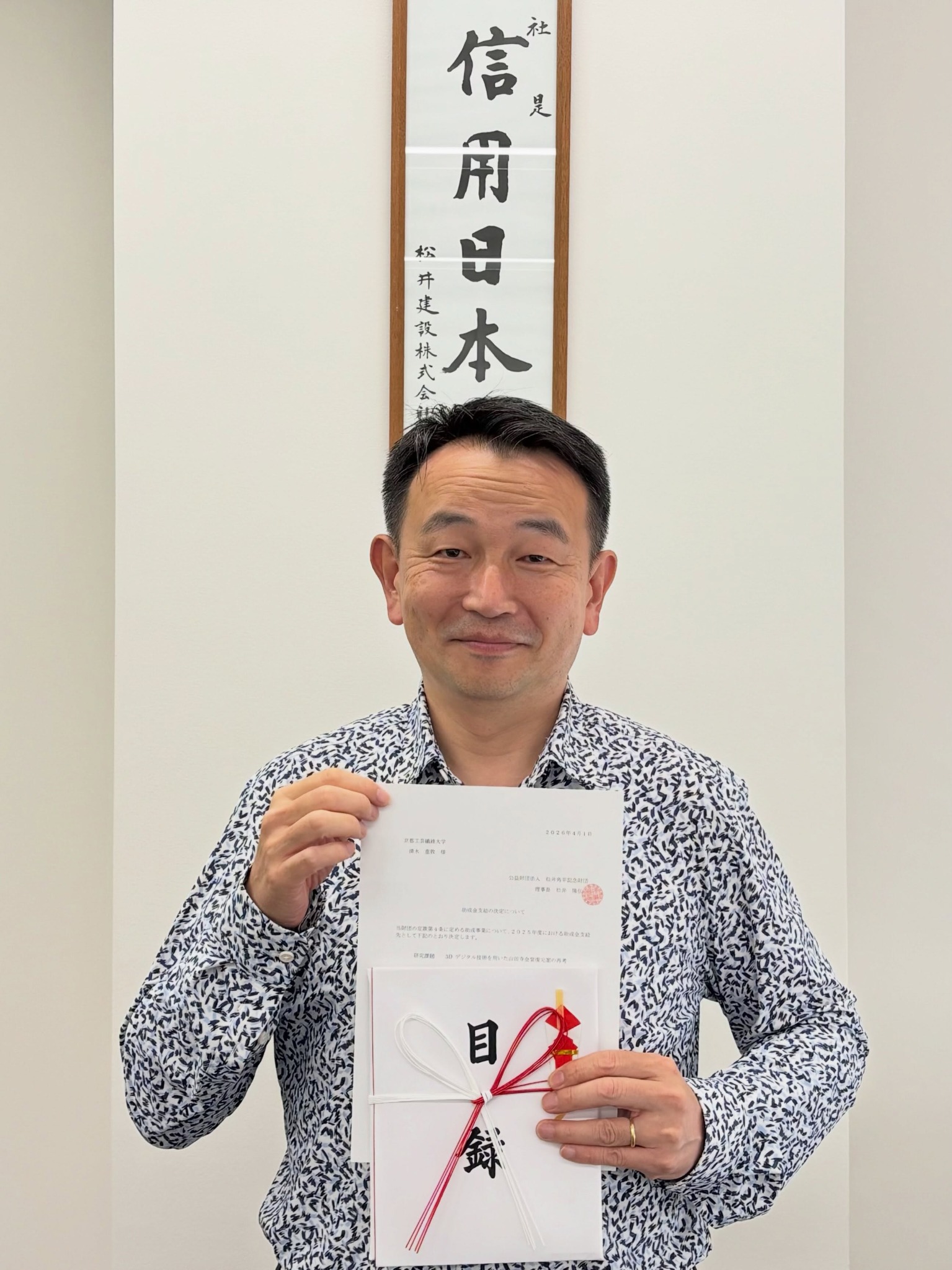 松井角平記念財団の研究助成金目録を手にする清水重敦